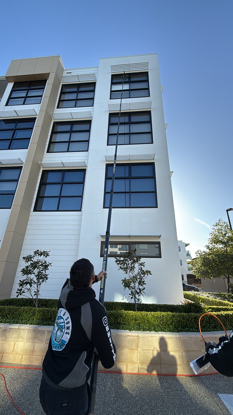 Rhett & Sons cleaning commercial glass with a water-fed pole